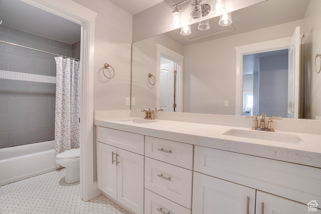 Bathroom featuring toilet, double vanity, and shower / bath combo with shower curtain