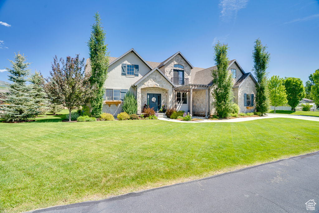 View of front of home featuring stone siding, a front lawn, and stucco siding