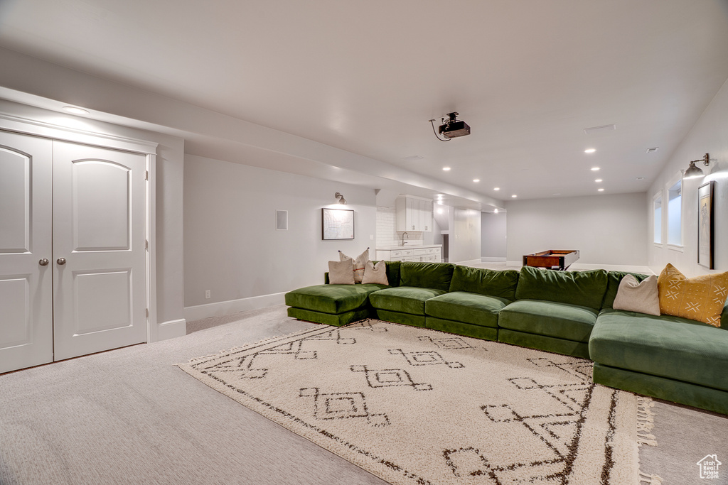 Carpeted living room with recessed lighting, baseboards, and a sink