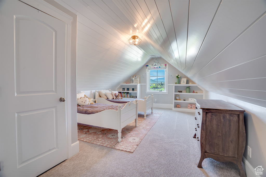 Carpeted bedroom with vaulted ceiling and baseboards