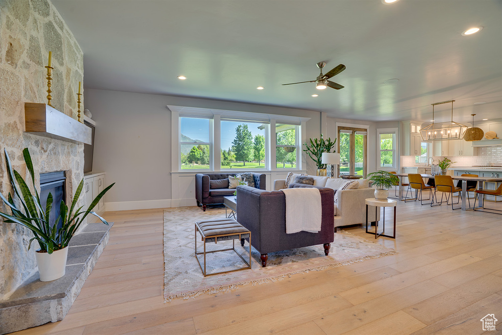 Living room with plenty of natural light, ceiling fan, a large fireplace, light wood-type flooring, and recessed lighting