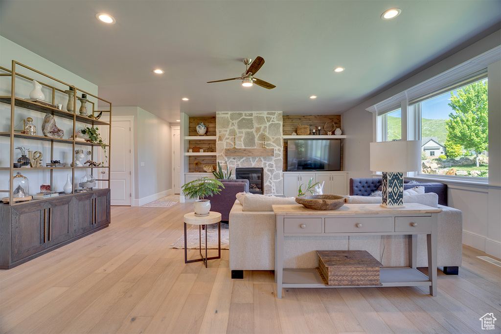 Living area with ceiling fan, light wood finished floors, a fireplace, recessed lighting, and baseboards