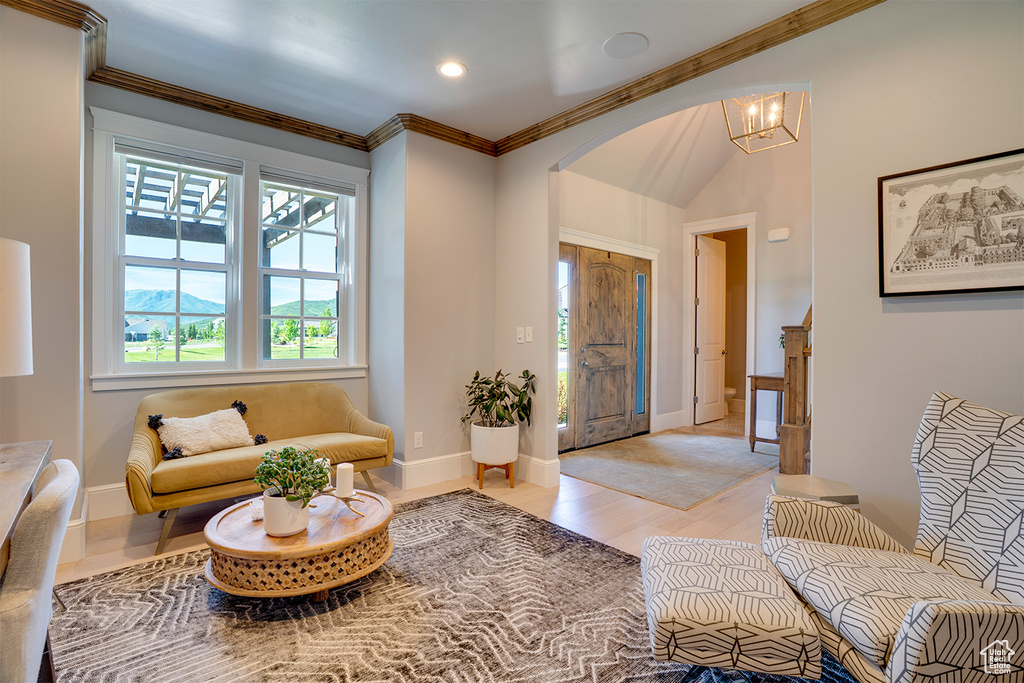 Foyer entrance featuring light wood-type flooring, arched walkways, crown molding, baseboards, and a chandelier