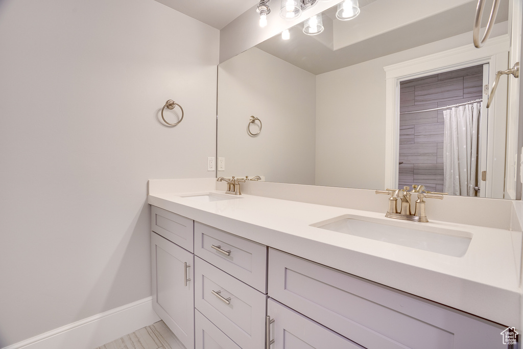Full bath featuring double vanity and baseboards