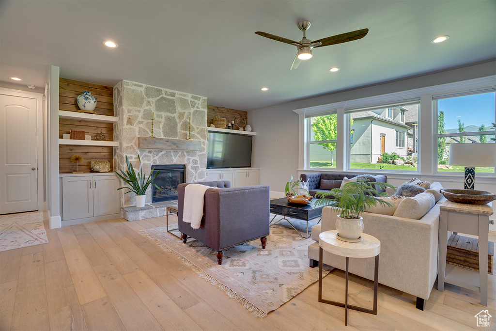 Living area with light wood-type flooring, recessed lighting, a stone fireplace, and ceiling fan