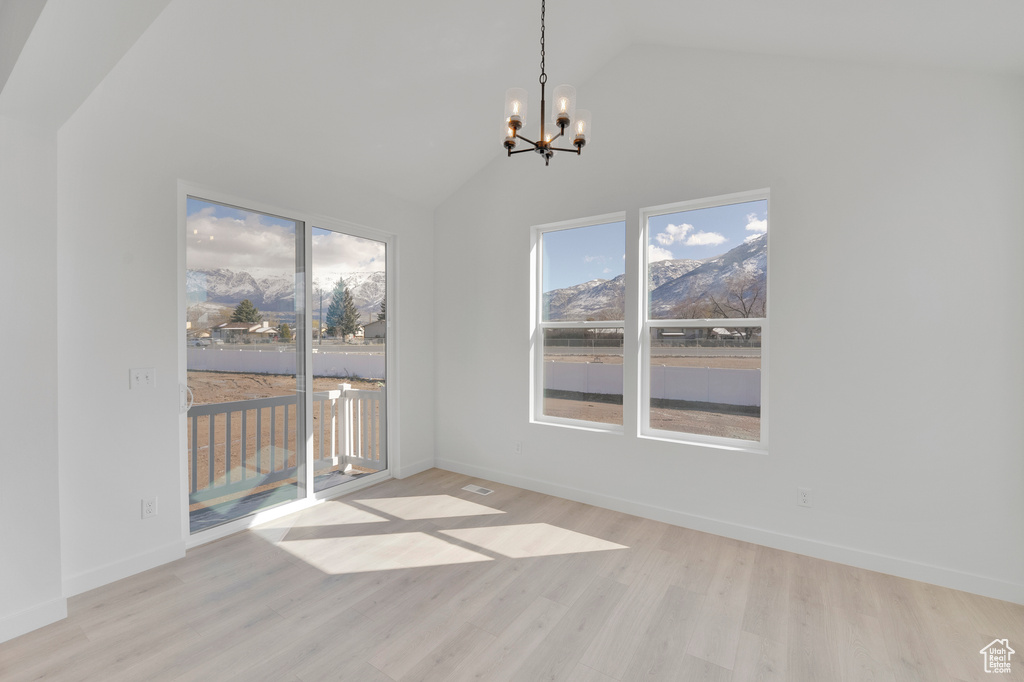 Unfurnished dining area featuring a chandelier, lofted ceiling, light wood finished floors, and baseboards