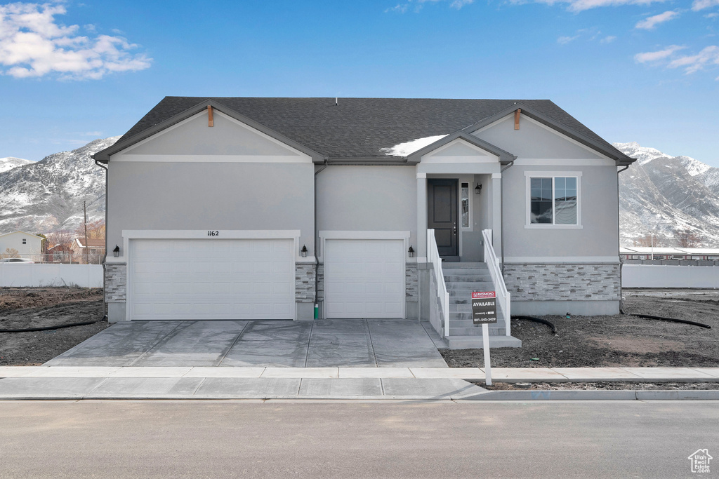 Ranch-style house featuring a mountain view, stone siding, stucco siding, and driveway