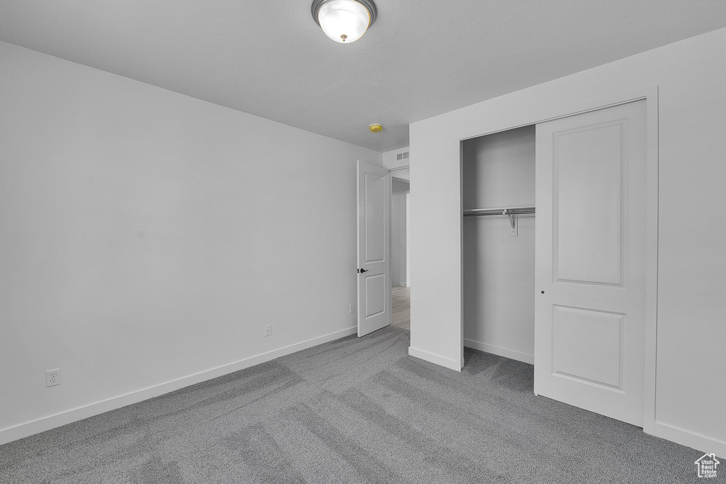 Unfurnished bedroom with carpet floors, baseboards, and a closet