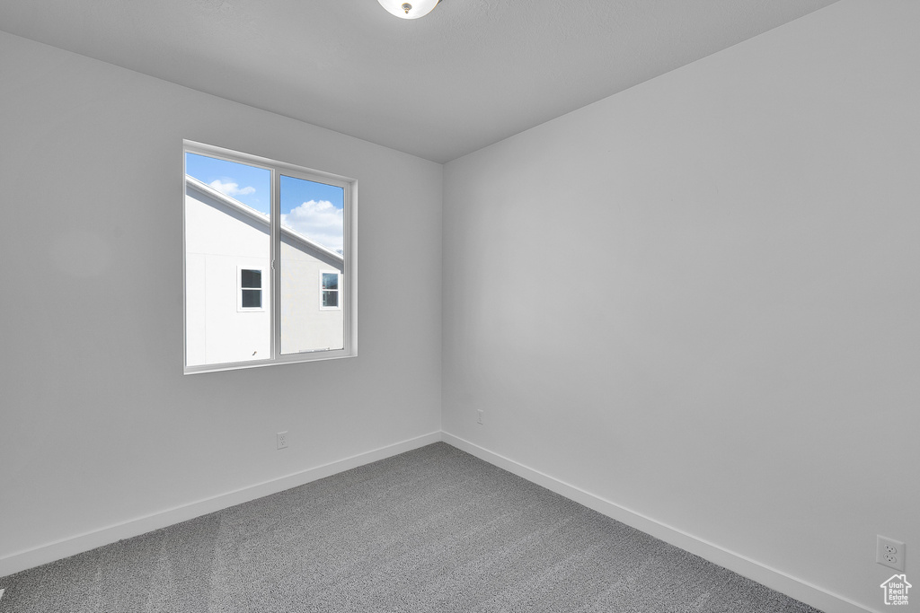 Spare room with dark carpet and baseboards