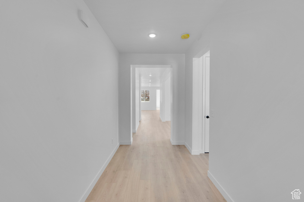 Hallway featuring light wood finished floors, baseboards, and recessed lighting