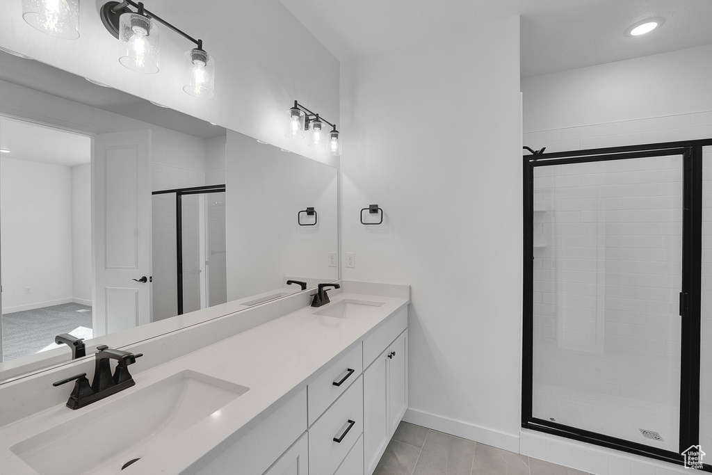 Bathroom with a shower stall, double vanity, baseboards, recessed lighting, and tile patterned flooring