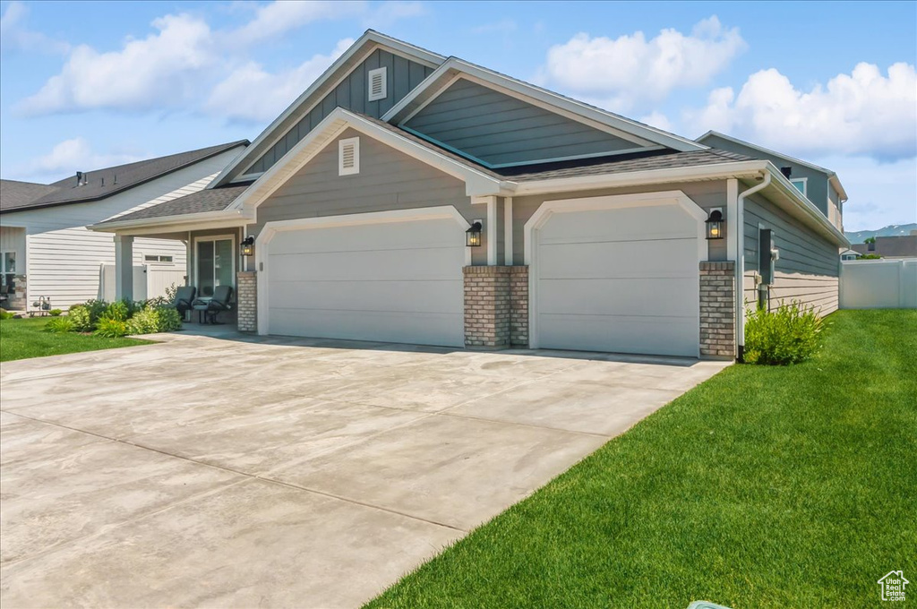 Craftsman-style house with an attached garage, a front yard, driveway, brick siding, and board and batten siding