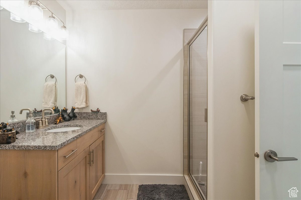 Bathroom featuring vanity, a shower stall, and baseboards