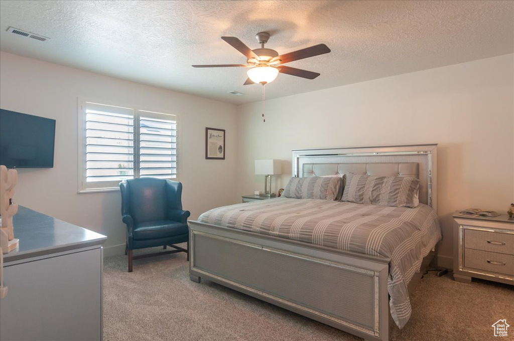 Bedroom featuring light colored carpet, a textured ceiling, and a ceiling fan