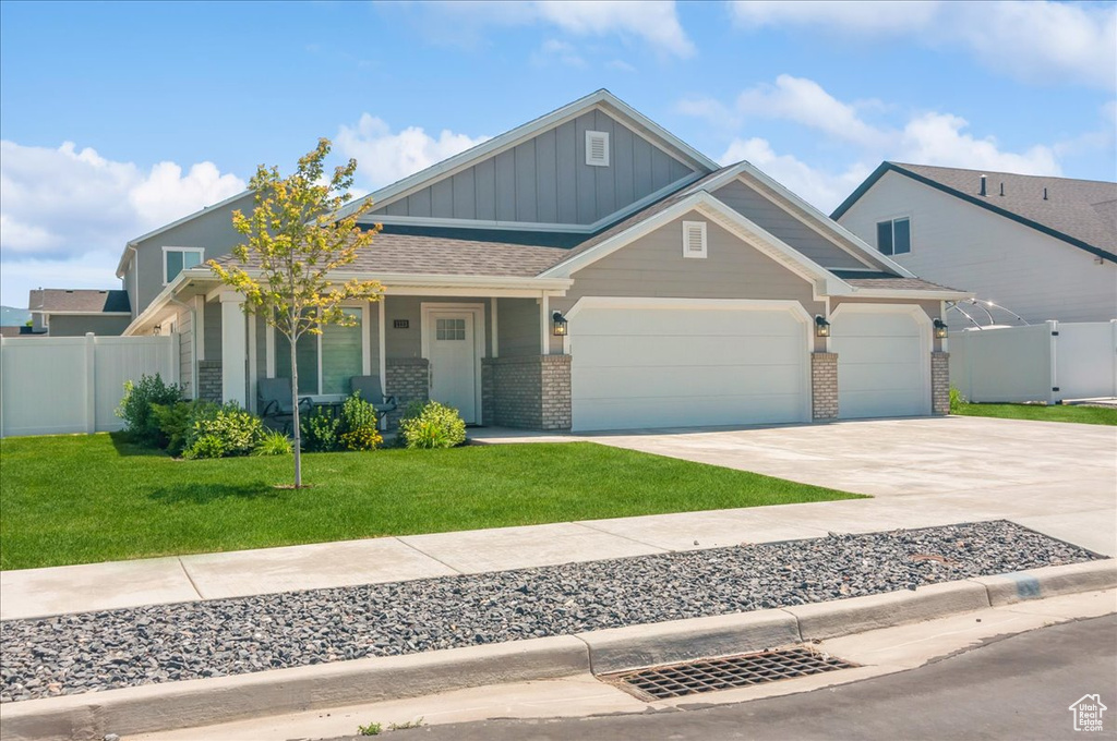 Craftsman-style house featuring board and batten siding, a garage, driveway, brick siding, and a porch