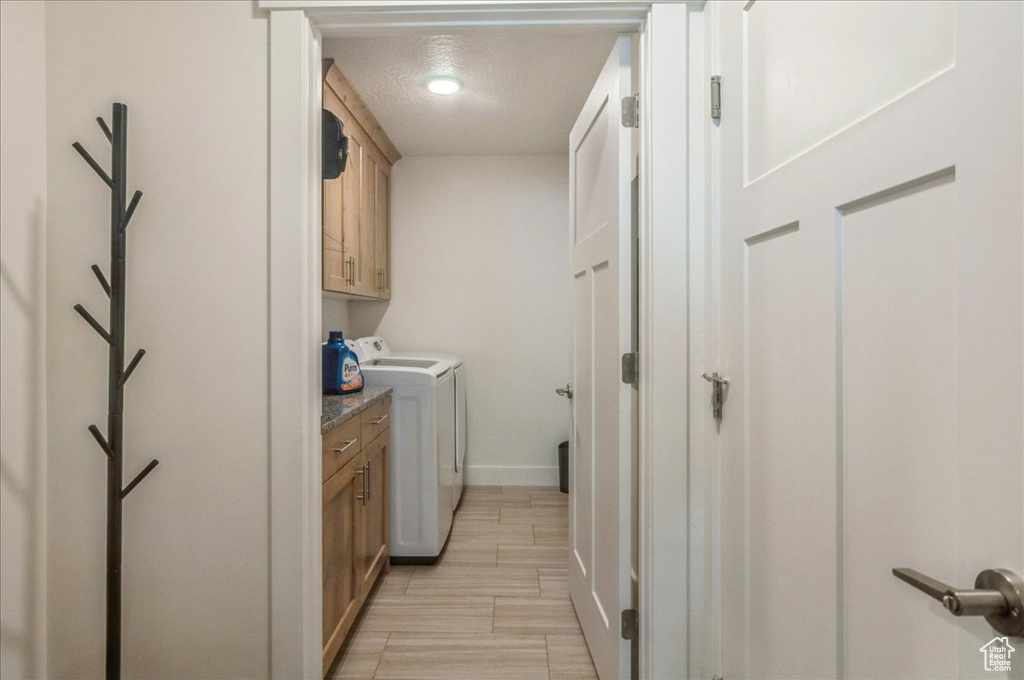 Laundry room with cabinet space, separate washer and dryer, baseboards, and a textured ceiling