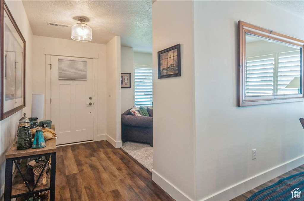 Entryway with a textured ceiling, dark wood-style floors, and baseboards