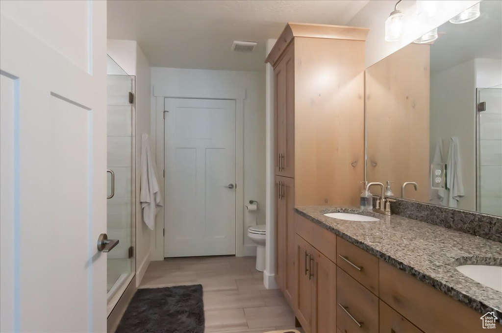 Full bath with double vanity, a stall shower, and toilet
