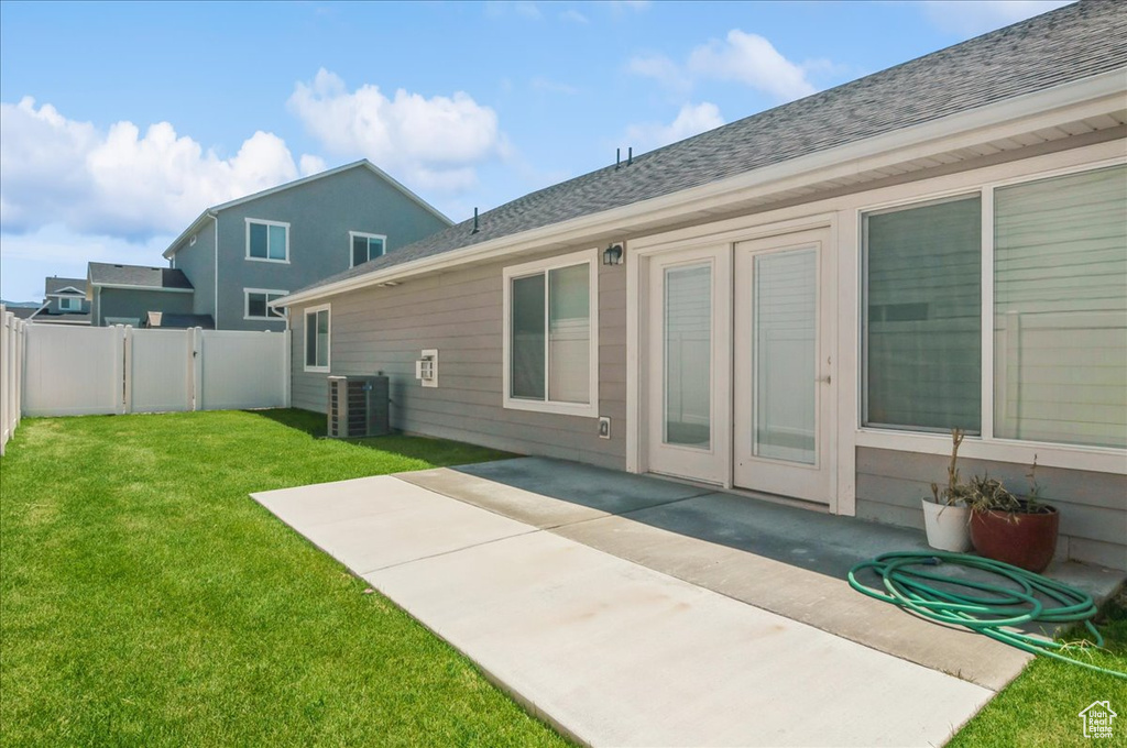 Back of house featuring central AC, a patio area, and roof with shingles