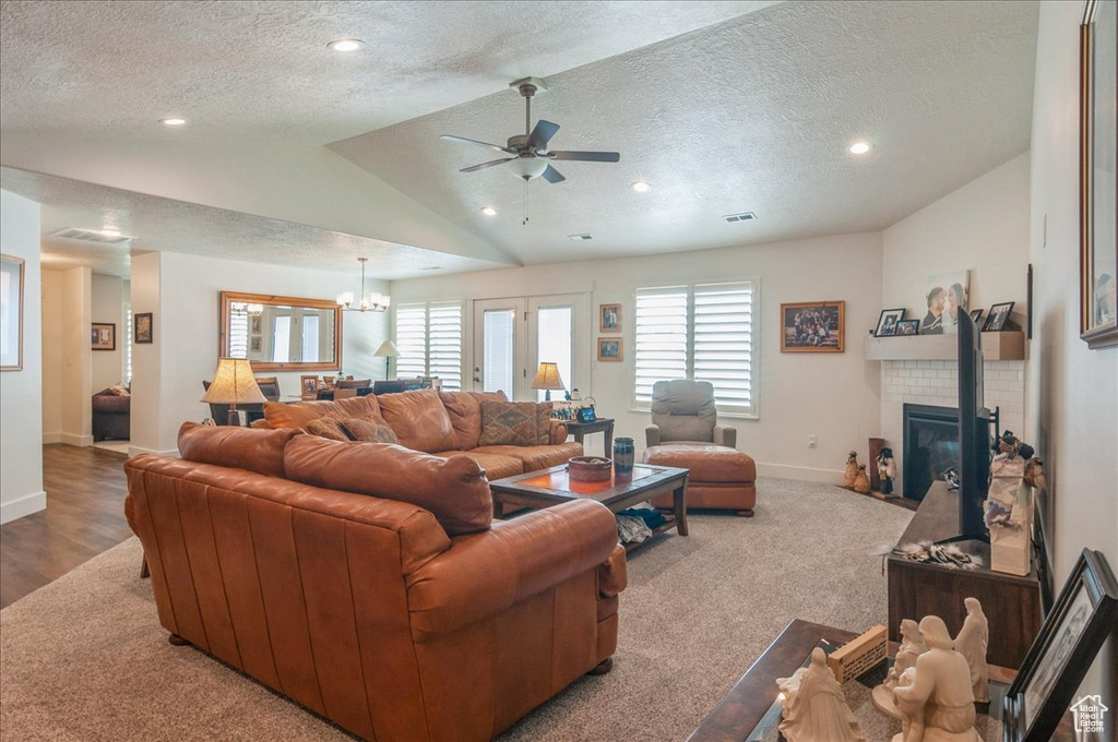 Living room with vaulted ceiling, a textured ceiling, baseboards, a ceiling fan, and a tile fireplace
