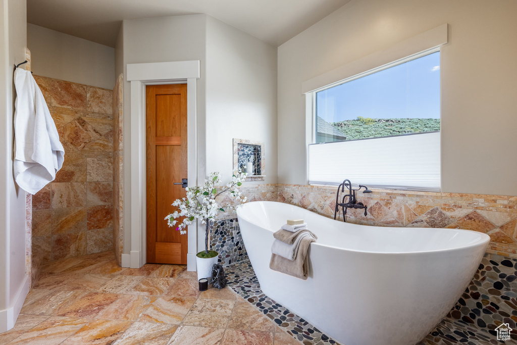 Full bathroom with a freestanding bath and tile walls