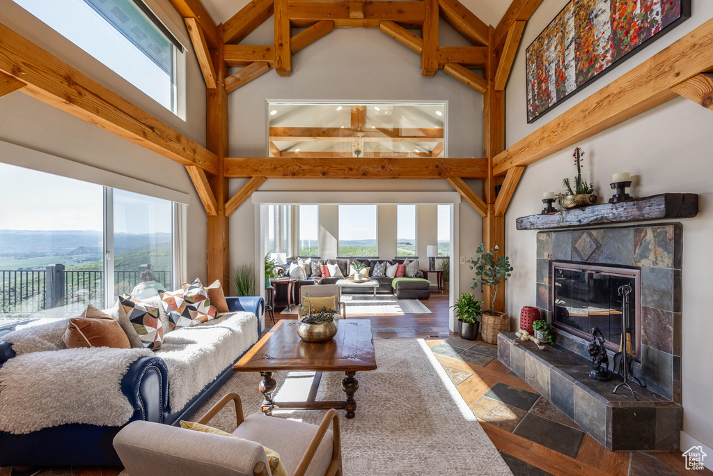 Living room with high vaulted ceiling, plenty of natural light, a fireplace, and beamed ceiling