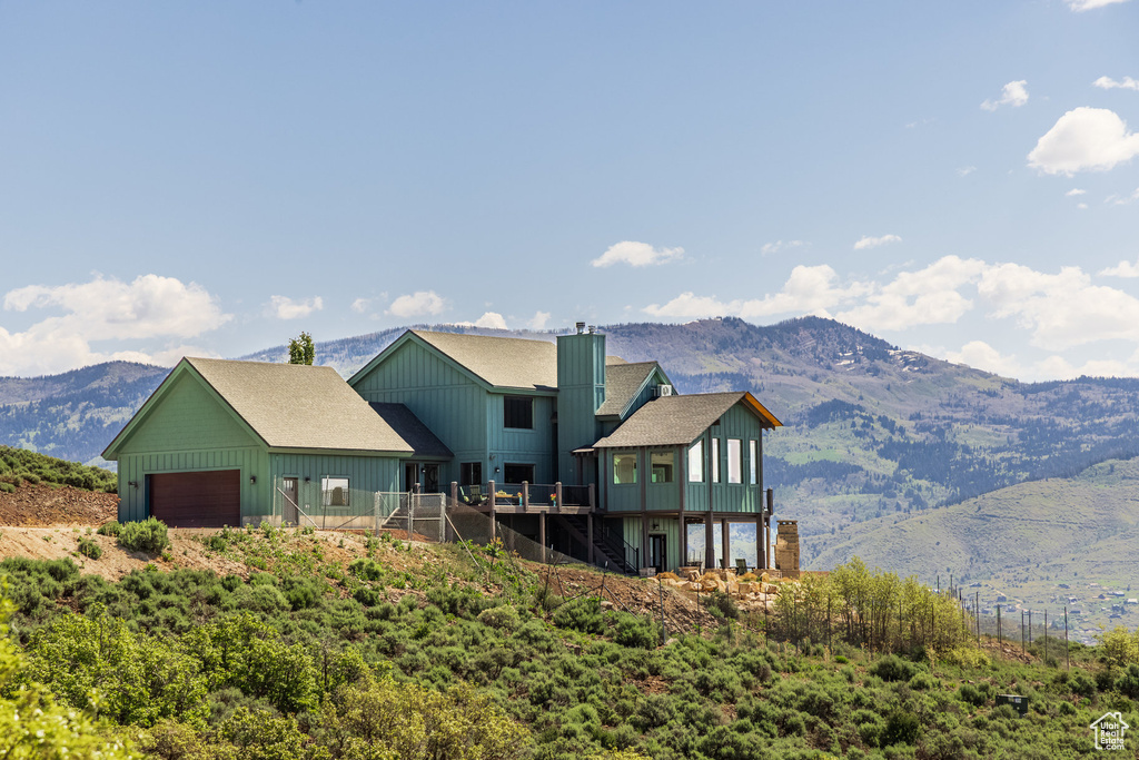 Back of property featuring a garage, board and batten siding, stairway, a deck with mountain view, and a chimney