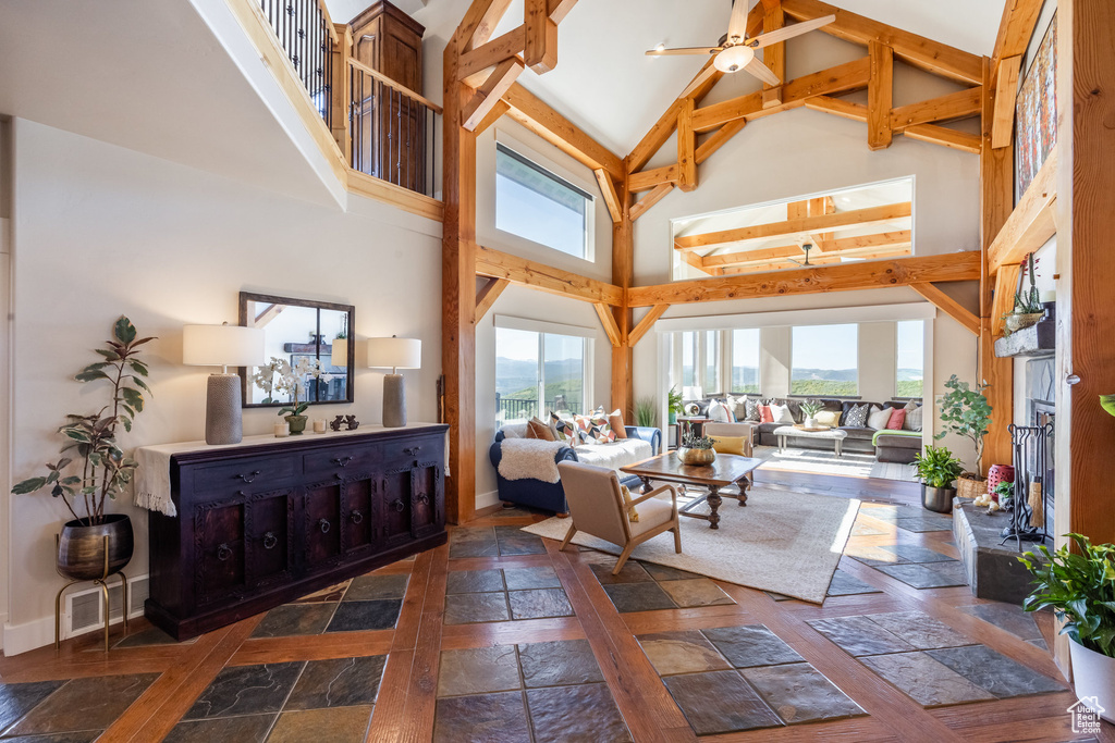 Living room with high vaulted ceiling, baseboards, beamed ceiling, and a ceiling fan