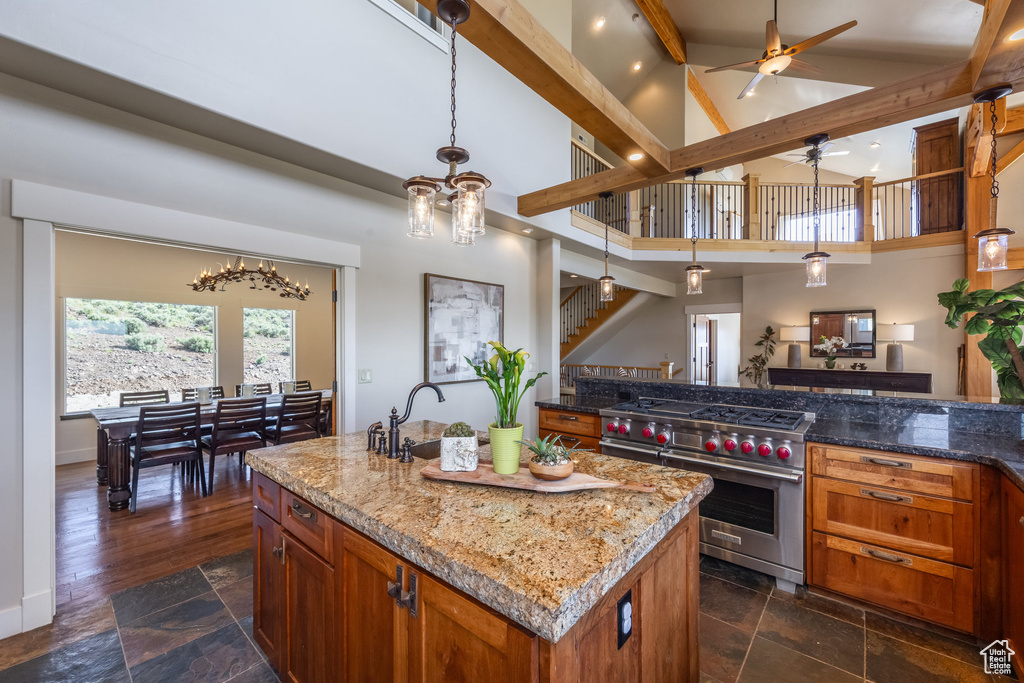 Kitchen with luxury range, ceiling fan, stone tile flooring, brown cabinetry, and high vaulted ceiling