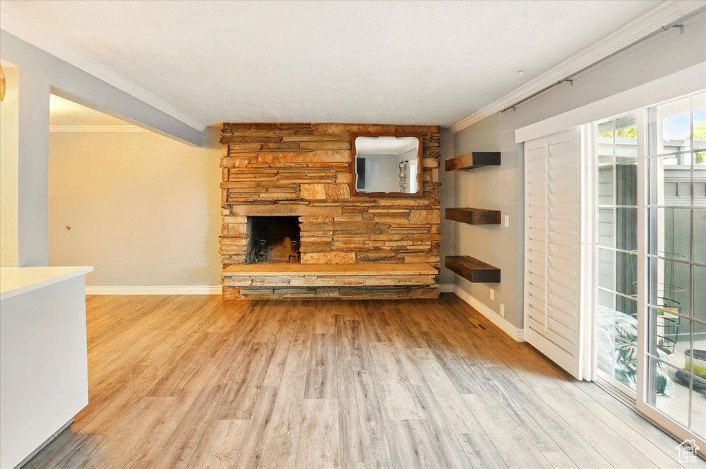 Unfurnished living room featuring ornamental molding, wood finished floors, a fireplace, and baseboards