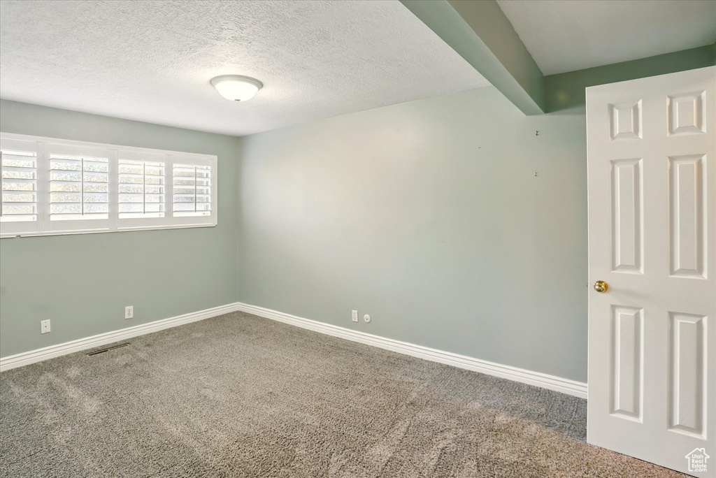 Carpeted spare room featuring baseboards and a textured ceiling