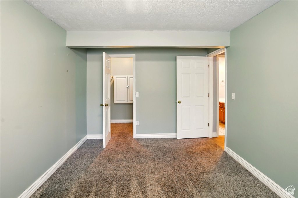 Unfurnished bedroom with carpet flooring, a textured ceiling, and baseboards