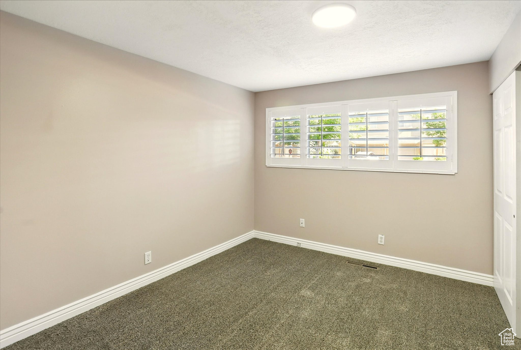 Unfurnished room with dark colored carpet and baseboards