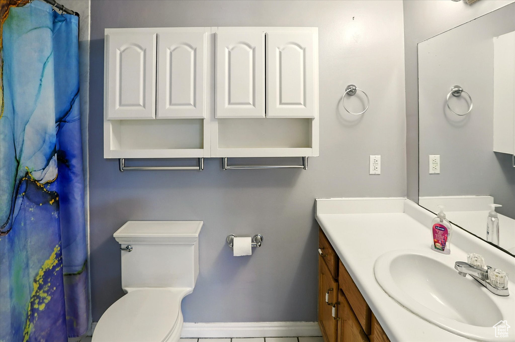 Full bathroom with vanity, toilet, tile patterned flooring, baseboards, and curtained shower