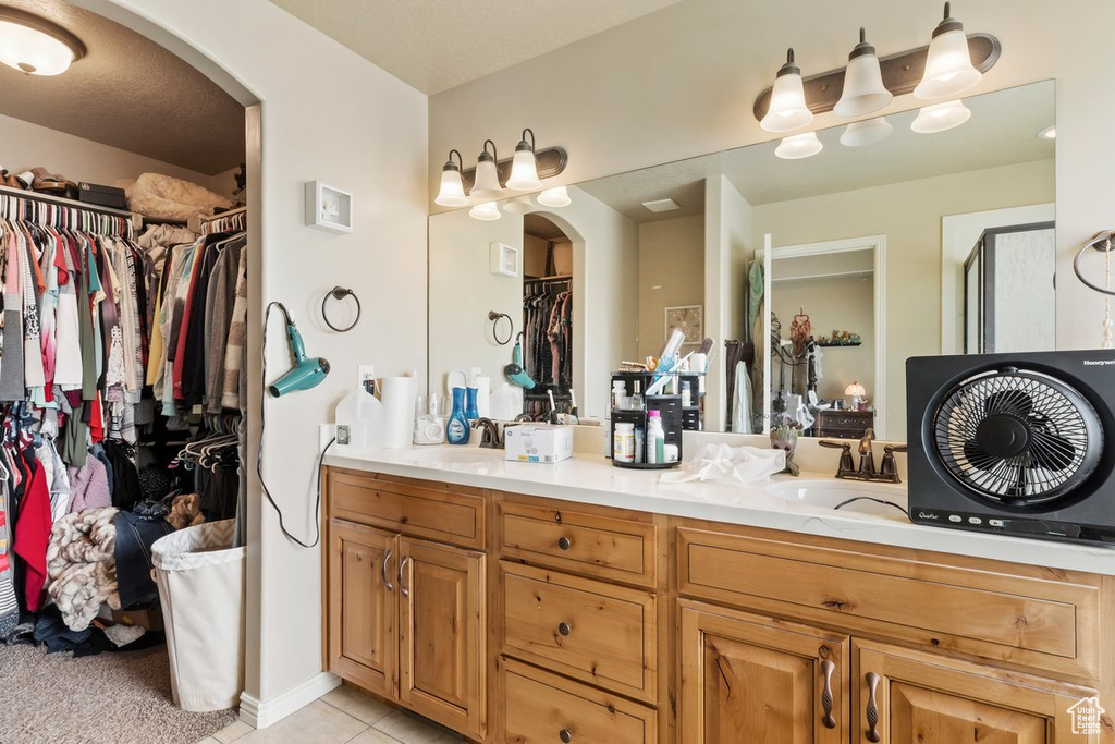 Bathroom featuring double vanity, a spacious closet, and tile patterned flooring