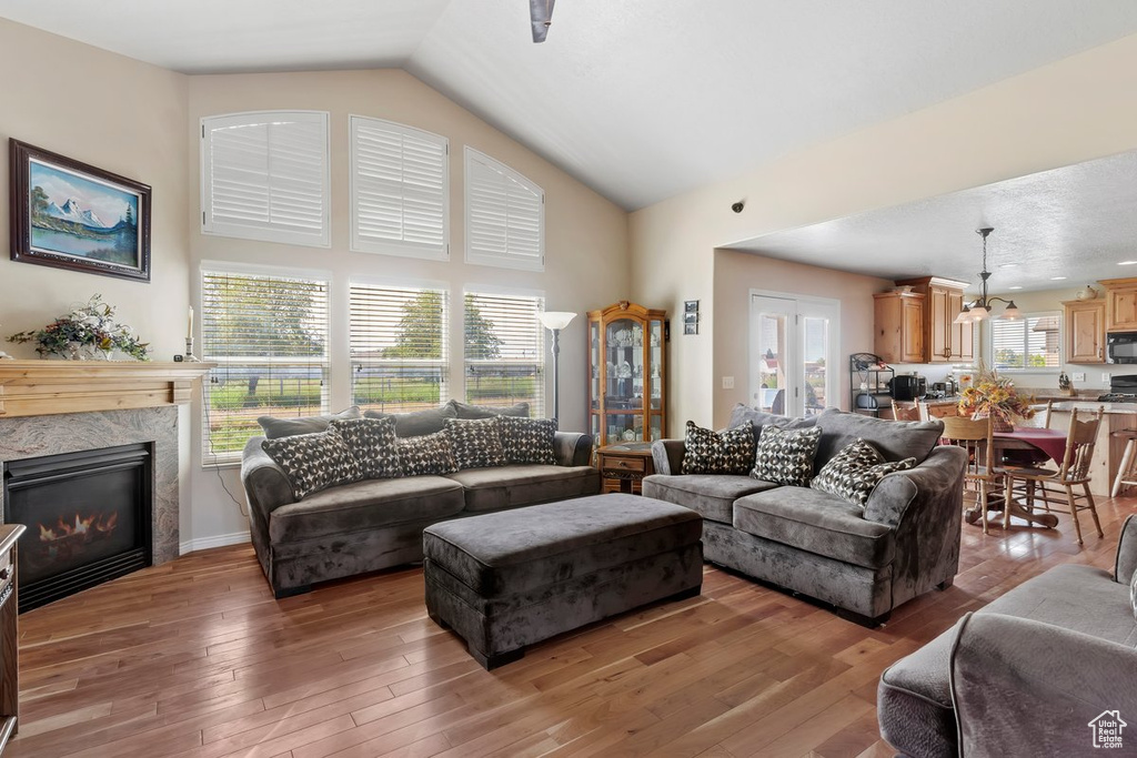 Living area with a premium fireplace, light wood-type flooring, and high vaulted ceiling
