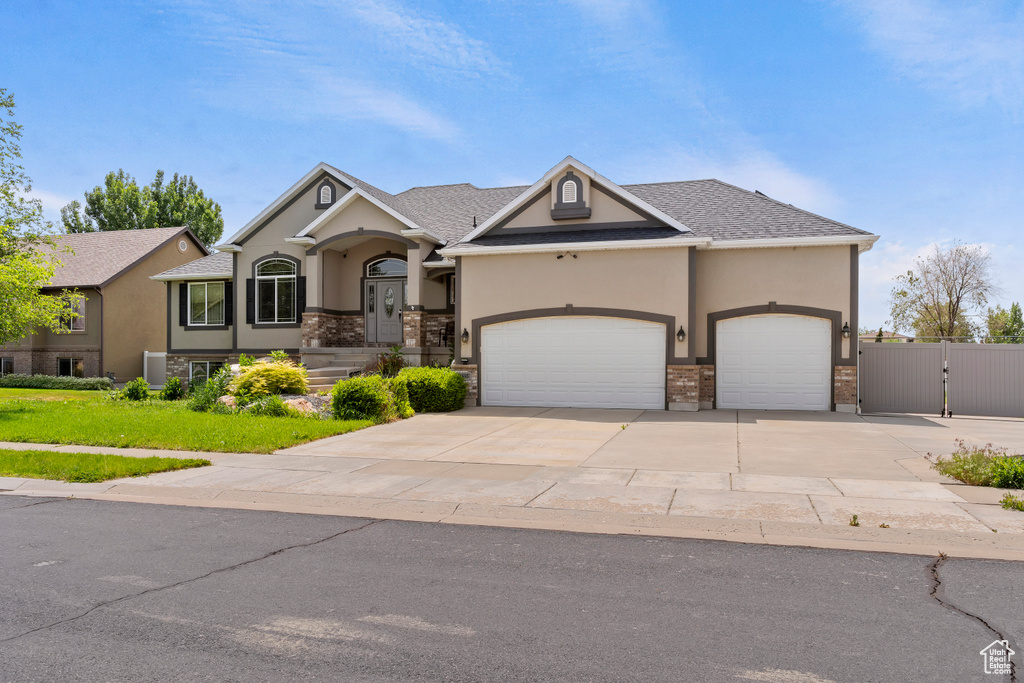View of front of property featuring stucco siding, a garage, driveway, and a gate
