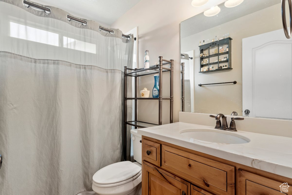 Bathroom featuring toilet, vanity, and curtained shower