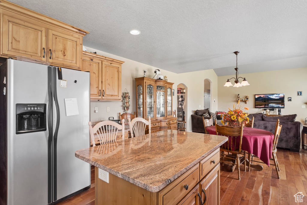 Kitchen featuring stainless steel fridge with ice dispenser, open floor plan, dark wood-style flooring, arched walkways, and recessed lighting
