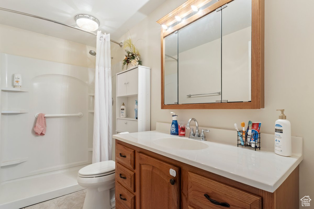 Bathroom with vanity, a shower with curtain, toilet, and tile patterned flooring