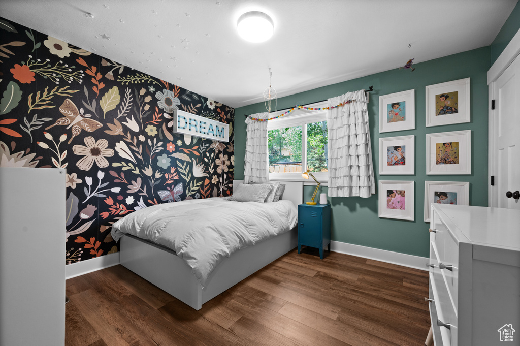 Bedroom featuring baseboards, dark wood-type flooring, and wallpapered walls