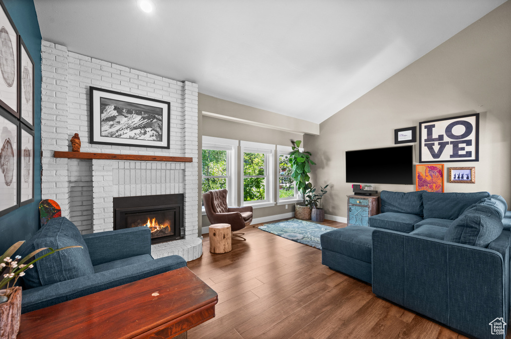 Living room featuring lofted ceiling, a fireplace, wood finished floors, and baseboards