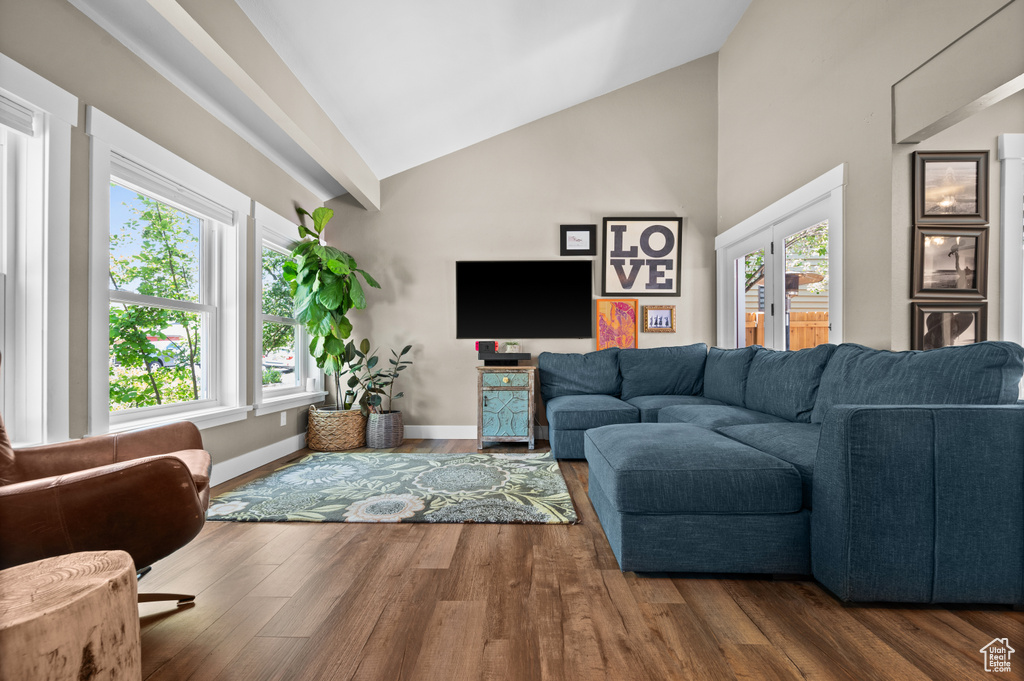 Living room featuring wood finished floors, high vaulted ceiling, and baseboards