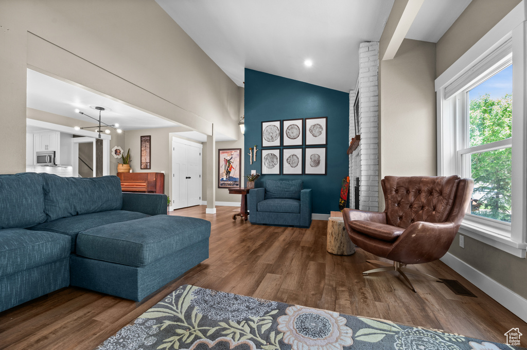 Living room with lofted ceiling, wood finished floors, stairway, and baseboards