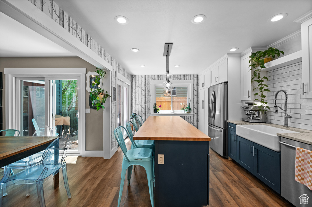 Kitchen with wood counters, stainless steel appliances, a sink, plenty of natural light, and recessed lighting