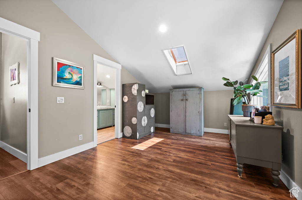 Interior space featuring lofted ceiling, a skylight, dark wood-style flooring, and baseboards