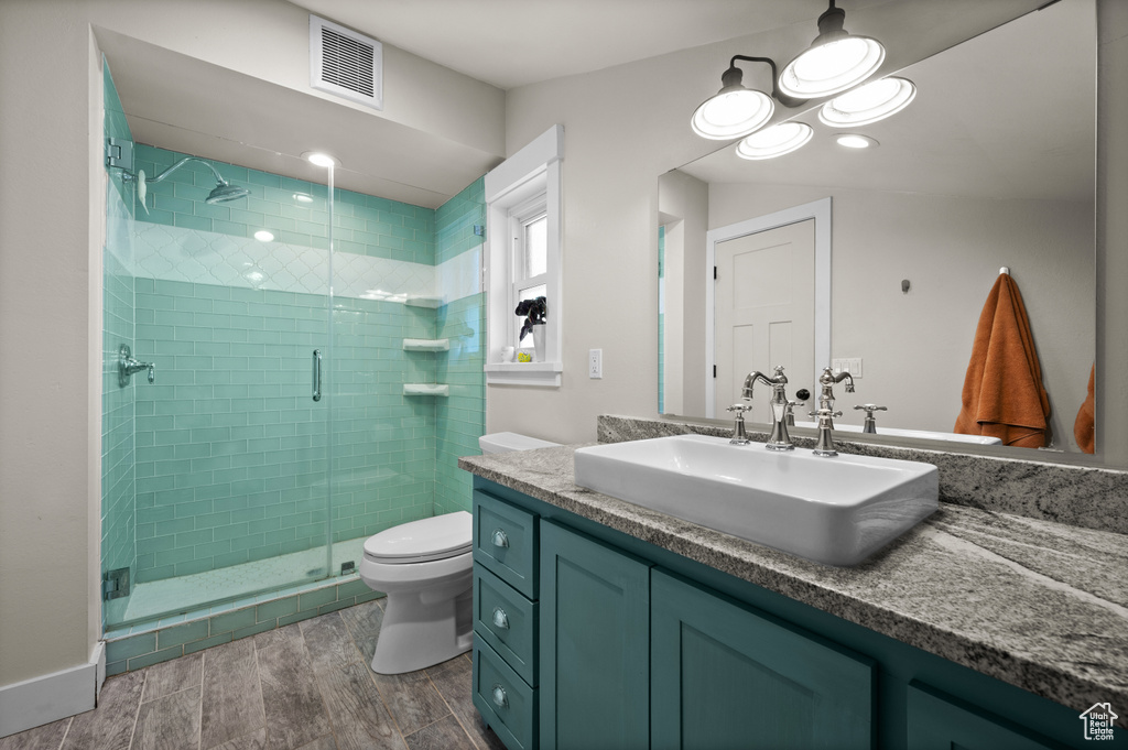 Bathroom featuring vanity, a shower stall, toilet, and wood finished floors