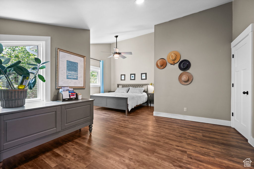 Bedroom featuring multiple windows, vaulted ceiling, dark wood finished floors, baseboards, and ceiling fan