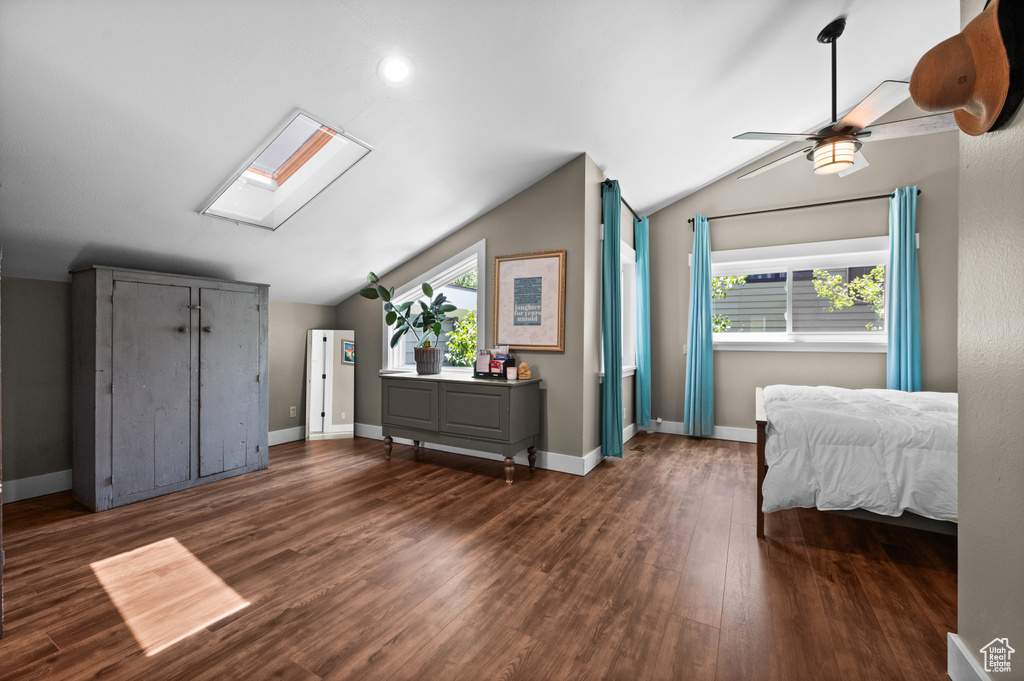 Bedroom featuring vaulted ceiling, a skylight, dark wood finished floors, and baseboards