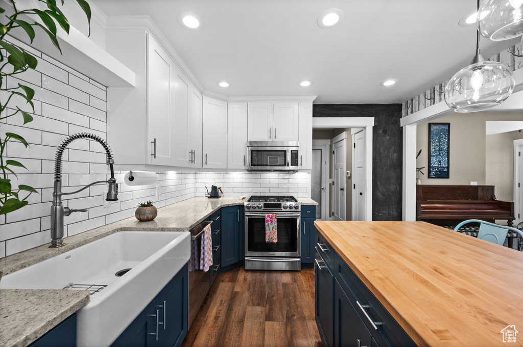 Kitchen featuring appliances with stainless steel finishes, wooden counters, blue cabinets, a sink, and white cabinets